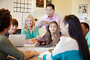 High School Students With Teacher In Class Using Laptops