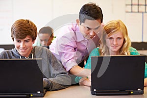 High School Students With Teacher In Class Using Laptops
