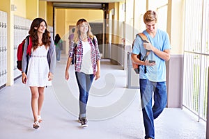 High School Students Walking In Hallway Using Mobile Phone