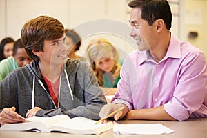 High School Teacher Helping Student With Written Work