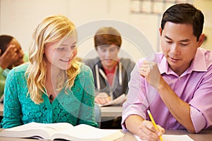 High School Teacher Helping Student With Written Work