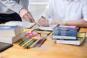 High school tutor or college student group sitting at desk in library studying and reading, doing homework and lesson practice