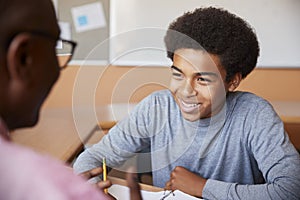 High School Tutor Giving Male Student One To One Tuition At Desk