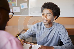 High School Tutor Giving Male Student One To One Tuition At Desk