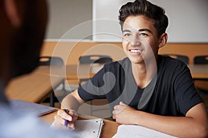 High School Tutor Giving Male Student One To One Tuition At Desk