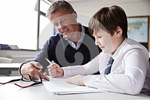 High School Tutor Giving Male Student Wearing Uniform One To One Tuition At Desk