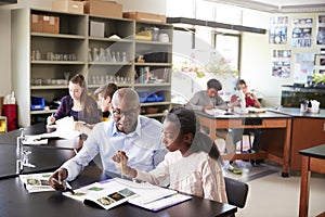 High School Tutor Sitting At Desk With Female Student In Biology Class photo