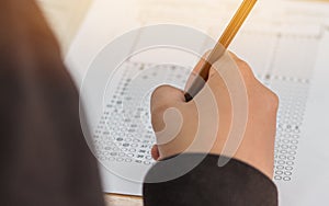 High school or university student hands taking exams, writing examination on paper answer sheet optical form of standardized test