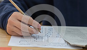 High school or university student hands taking exams, writing examination on paper answer sheet optical form of standardized test