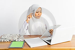 high school veiled girl at desk having trouble doing homework