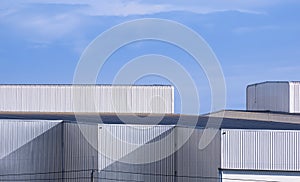 High section of modern corrugated iron industrial factory Buildings against blue sky background