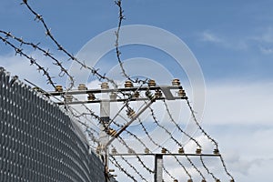 High Security Fence with electric barbed wire against a blue sky