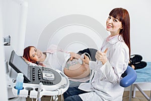 High-skilled professional attractive woman doctor doing 3d ultrasound on belly of pregnant woman in clinic, smiling to