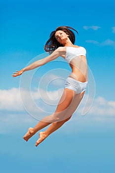 High in the Sky. a happy young woman jumping high in the sky with her body outstretched.