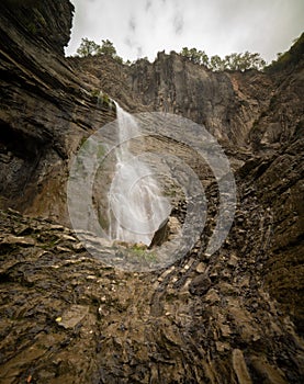 High small waterfall and steep rocks with green plants