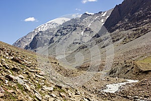 High snow capped Himalayan mountain peaks rising above a flowing river