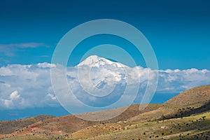 High snowy mountain Ararat behind the clouds on a sunny day, beautiful landscape