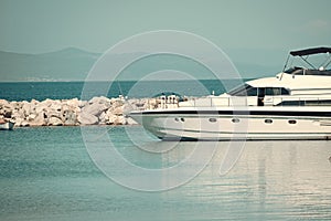 High speed boat, luxury yacht in dock in sea, blue sky on background. White luxury yacht, marine glides on sea surface