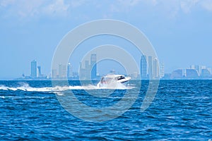 High-speed boat sails on the sea towards a skyscraper coastal city