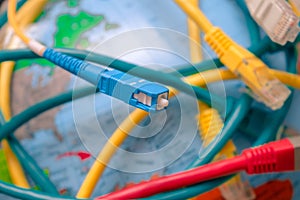 High-speed cable. Fiber optic patch cord is close-up on a background of the globe. Different Internet wires entangle the Earth. .