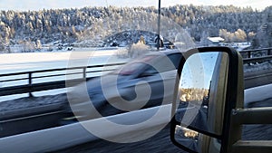 High speed car passing, rear view in mirror, and view over frozen lake