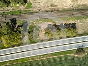 High-speed highway and railway, top view. Green field and blue sky.