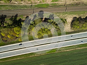 High-speed highway and railway, top view. Green field and blue sky.