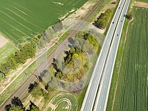 High-speed highway and railway, top view. Green field and blue sky.