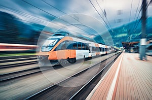 High speed orange train in motion on the railway station