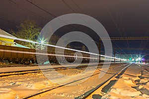 High speed passenger train on railroad tracks with motion blur effect near the railway station