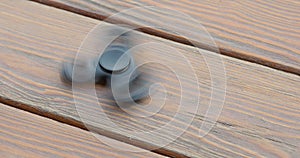 A high speed spinning hand spinner or fidget spinner over the wooden background.