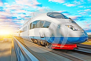 High speed train passenger locomotive in motion at the railway station at sunset with a beautiful picturesque sky.