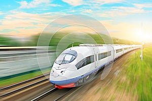 High speed train passenger locomotive in motion at the railway station at sunset with a beautiful picturesque sky.