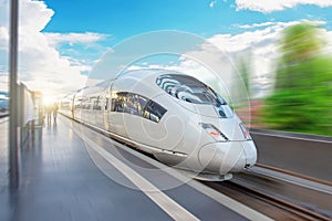 High speed train passes by the passenger station at fast velocity with the effect of movement