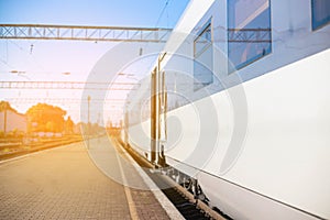 High-speed train on rails on the railway station platform on a sunny day. Modern intercity train on railway platform. Travel