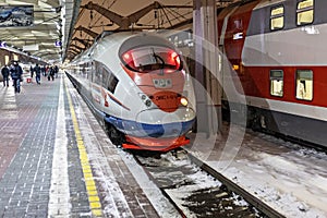 A high-speed train stands on the platform of the station waiting for departure. Winter