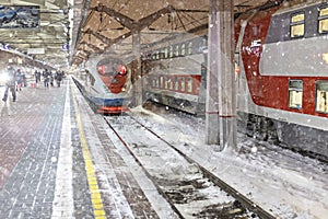 A high-speed train stands on the platform of the station waiting for departure. Winter, snowfall