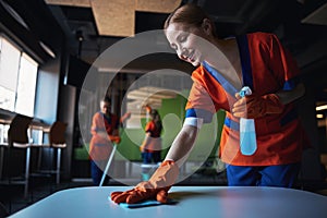 Three female workers using various janitorial supplies during the clean-up photo