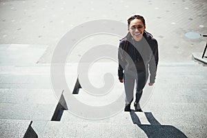 High-spirited woman with cornrows in activewear looking up