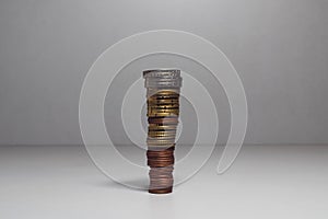 High stack of coins on gray background. Coins are placed from smaller to larger. Smaller coins at the bottom