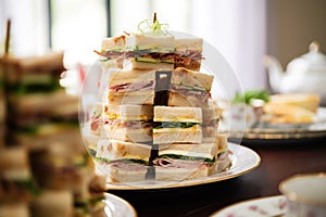 a high stack of cut clubhouse sandwiches for high-tea