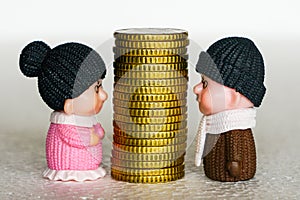 High stack of yellow coins between toy figures of elderly man and woman, money disputes concept photo