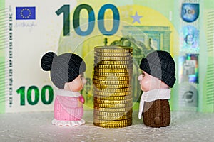 High stack of yellow coins between toy figures of elderly man and woman, money disputes concept photo