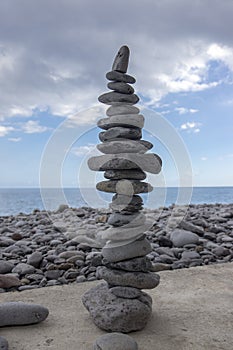 High stone cairn tower, poise stones, rock zen sculpture, light grey pebbles
