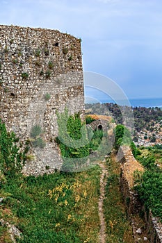 The high stone wall of the ancient Rozafa Castle and the walking path