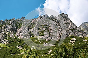 Vrchol Vysokých Tatier s modrou oblohou a oblakmi na pozadí na Slovensku. Turistické chodníky pre pešiu turistiku v