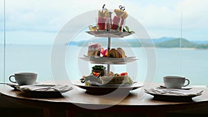 High tea set with assortment of sweets, cakes, sandwiches, fruit canape on table