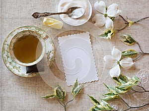 High Tea Table Place Setting with Cup and Saucer with sugar bowl, spoon, lemon and pretty white flowers.  It`s horizontal with an