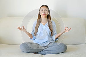 High-Tech Meditation. Young woman with wireless earphones using meditation app on smart phone sitting in lotus position on