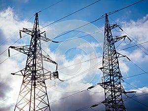 High voltage electricity pillars on the blue sky background with clouds. Metal bearing high voltage power line. High tech power